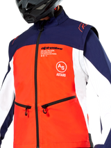 Alpinestars Lite-Dura Softshell Jacket in Navy Hot Orange and White, close-up view of the torso, featuring a bright orange front panel with white side panels and navy blue shoulders, zippered hand pockets, and prominent Alpinestars branding, worn by a rider with a black off-road helmet.
