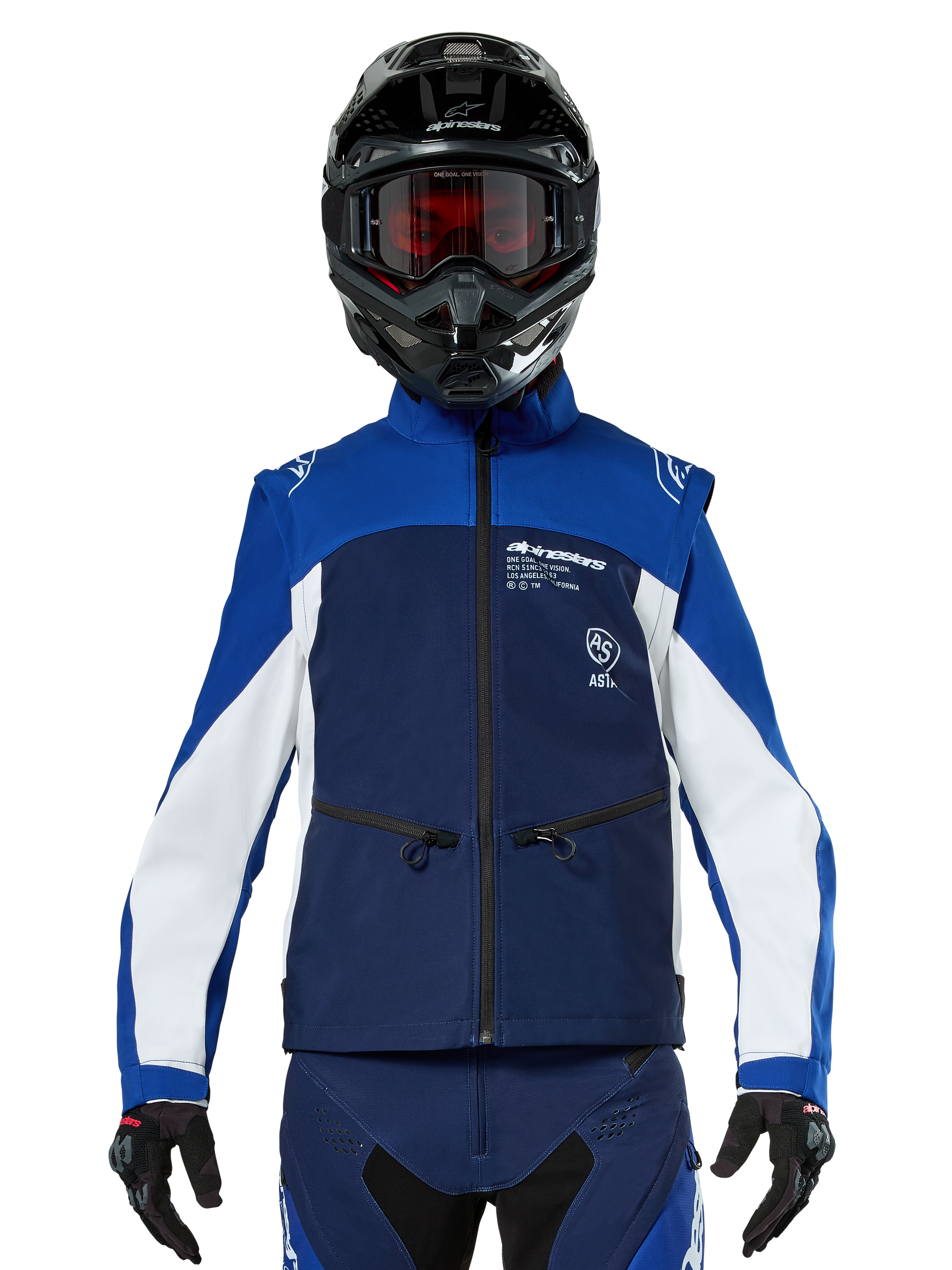 Motocross rider wearing the Alpinestars Lite-Dura Softshell Jacket in Navy Bright Blue White, front view, paired with a black helmet and red-tinted goggles, featuring a technical windproof design with zippered pockets and white accents for off-road enduro riding