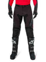 Alpinestars Pro-Dura Pants, Black and Magnet Enduro Pants, worn with a red long-sleeve jersey and black motocross boots, featuring gray Alpinestars branding and durable ripstop construction for off-road riding