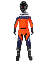 Motocross rider wearing Alpinestars Pro-Dura Pants in Navy Hot Orange White, featuring a matching long-sleeve jersey, black helmet with goggles, black gloves, and black motocross boots, complete off-road racing gear.
