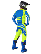 Motocross rider from behind wearing Alpinestars 2025 Fluid Haul Pants and matching jersey in Yellow Fluo and Blue, coordinated with blue boots and a black Alpinestars helmet, professional off-road racing gear