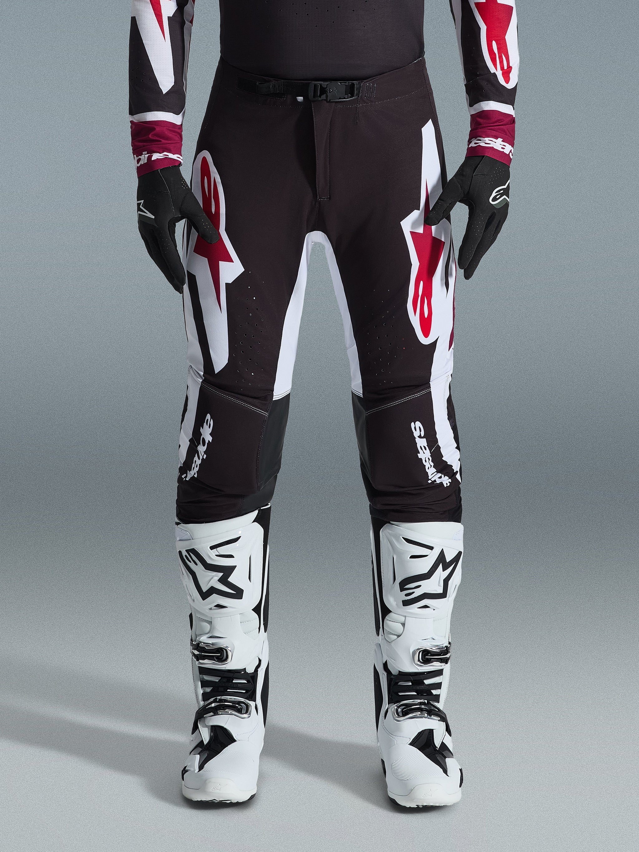 Alpinestars 2026 Supertech AFD Vista Pants, Motocross Pants, Black Red and White, featuring large graphic logos on the thighs and knees, worn with white racing boots and black gloves, athletic race-ready design for elite off-road competition