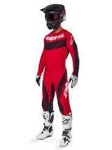 Motocross rider wearing complete racing gear featuring Alpinestars 2025 Techstar Dreem Pants in Bright Red and Black, matching red and black jersey with white logo, black helmet, and white and black boots, coordinated outfit for off-road racing