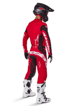 Alpinestars 2025 Techstar Dreem Pants, Motocross Pants, Bright Red and Black, worn by a rider from a rear perspective in a full racing kit with matching red jersey, black helmet, and white boots, featuring bold white Alpinestars branding and black stretch panels.