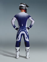 Alpinestars 2026 Supertech Scenz Pants, Motocross Pants, Light Gray and Dark Blue, rear view of a rider wearing a matching gear set with speckled gradient graphics, white boots and black helmet, professional athletic fit for off-road racing