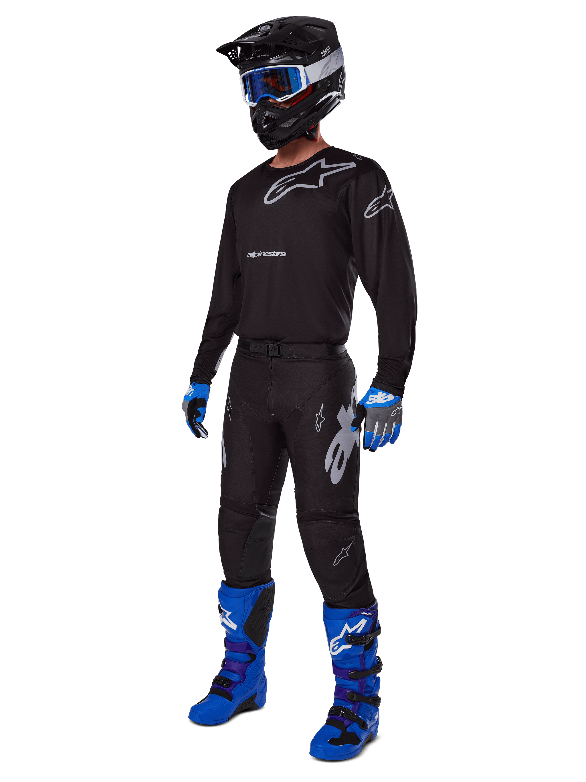 Motocross rider wearing complete Alpinestars racing gear, 2025 Racer Graphite Pants in Black and Gray, matching black jersey with grey logos, black helmet with blue goggles, bright blue and purple boots, and blue and grey gloves, coordinated outfit for off-road racing