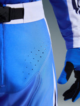 Alpinestars 2026 Techstar Knif Pants, Ucla Blue and White, close-up of hip area showing laser-cut perforations for ventilation, SX2 magnetic buckle waist closure, and matching motocross gloves