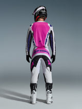 Motocross rider from the back wearing Alpinestars 2026 Fluid Grid Pants and matching jersey, Pink White and Black with Purple branding, Black helmet, White and Black boots, coordinated racing outfit for off-road motocross