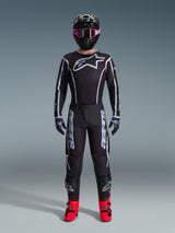 Alpinestars 2026 Fluid Apex Gear Set, Motocross Outfit, Black with Gray accents, jersey featuring large white Astars logo, matching pants with bold branding, black helmet with pink goggles, and bright red boots, complete off-road racing kit