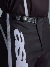 Alpinestars 2026 Fluid Apex Pants, Motocross Pants, Black and Gray, close-up detail of the integrated ratchet closure system for a secure fit, featuring white logo graphics on durable 600D polyfabric.