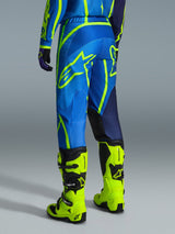 Alpinestars 2026 Fluid Apex Pants, Motocross Pants, Blue and Yellow Fluo, back view of rider wearing matching gear and fluorescent yellow boots, featuring bold Alpinestars logos and ergonomic design