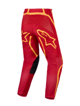 Alpinestars Fluid Apex V2 Motocross Pants in Fire Red and Gold, featuring a reinforced seat and large star graphics.