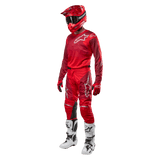 Motocross rider wearing complete racing gear, Alpinestars 2024 Racer Hoen Pants and jersey in Mars Red Burgundy, red helmet, red gloves, and white and black boots, coordinated outfit for off-road racing