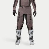 Alpinestars 2024 Fluid Lurv Pants, Motocross Pants, Mud Black, worn with matching jersey, black gloves, and white boots, featuring large black logos on thighs, ergonomic fit, and durable material for off-road racing