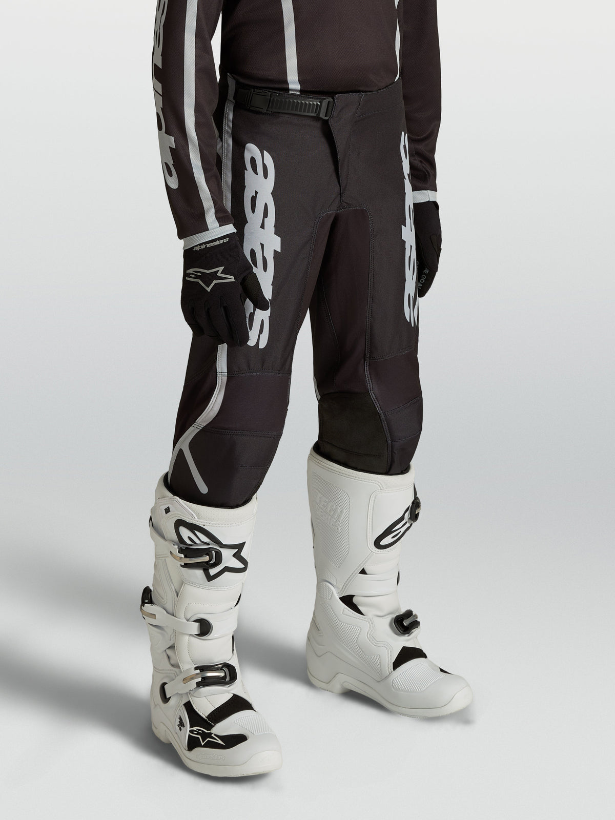 Alpinestars Youth Fluid Apex V2 Pants, black and silver motocross gear for young riders, featuring an ergonomic pre-curved fit.