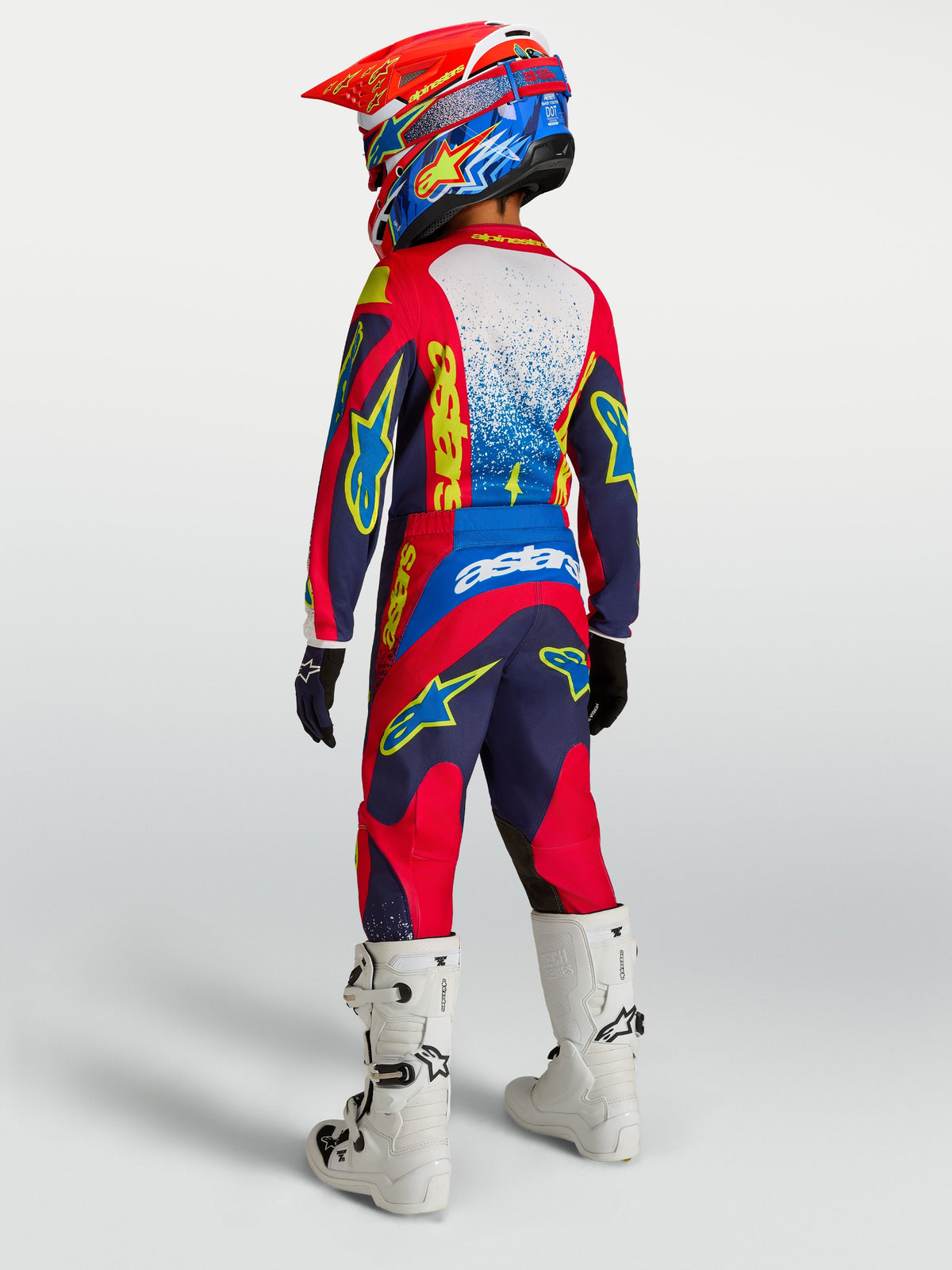 Alpinestars Youth Fluid Drag Pants, navy blue and fire red motocross trousers with reinforced seat and white racing boots.