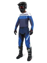 Motocross rider wearing complete racing gear, Pro-Dura Jersey in Navy Bright Blue and White, matching blue and navy pants, black helmet with red goggles, black boots with white accents, and black gloves, coordinated outfit for enduro and off-road riding