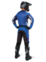 Motocross rider from the back wearing Alpinestars Pro-Dura Jersey in Navy and Bright Blue, matching blue and black pants, black motocross helmet with goggles, and black boots, showing a coordinated off-road racing outfit