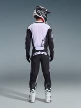 Rear view of a motocross rider wearing the 2026 Racer Air Riway Jersey in Black and White, featuring a breathable mesh back panel, paired with matching black motocross pants with white 'astars' branding, a black and white helmet, and white racing boots.