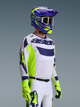 Motocross rider wearing the Alpinestars 2026 Racer Air Riway Jersey, Light Gray with Yellow Fluo and Blue accents, paired with a matching blue and yellow helmet and fluo yellow gloves, featuring breathable mesh construction and professional race styling for off-road performance.