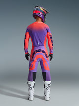 Motocross rider from behind wearing the 2026 Supertech Scenz Gear Set in Hot Coral Purple, vibrant jersey and pants with gradient transition, featuring Alpinestars logos, matching helmet, white and black boots, and black gloves, professional gear for elite off-road racing.