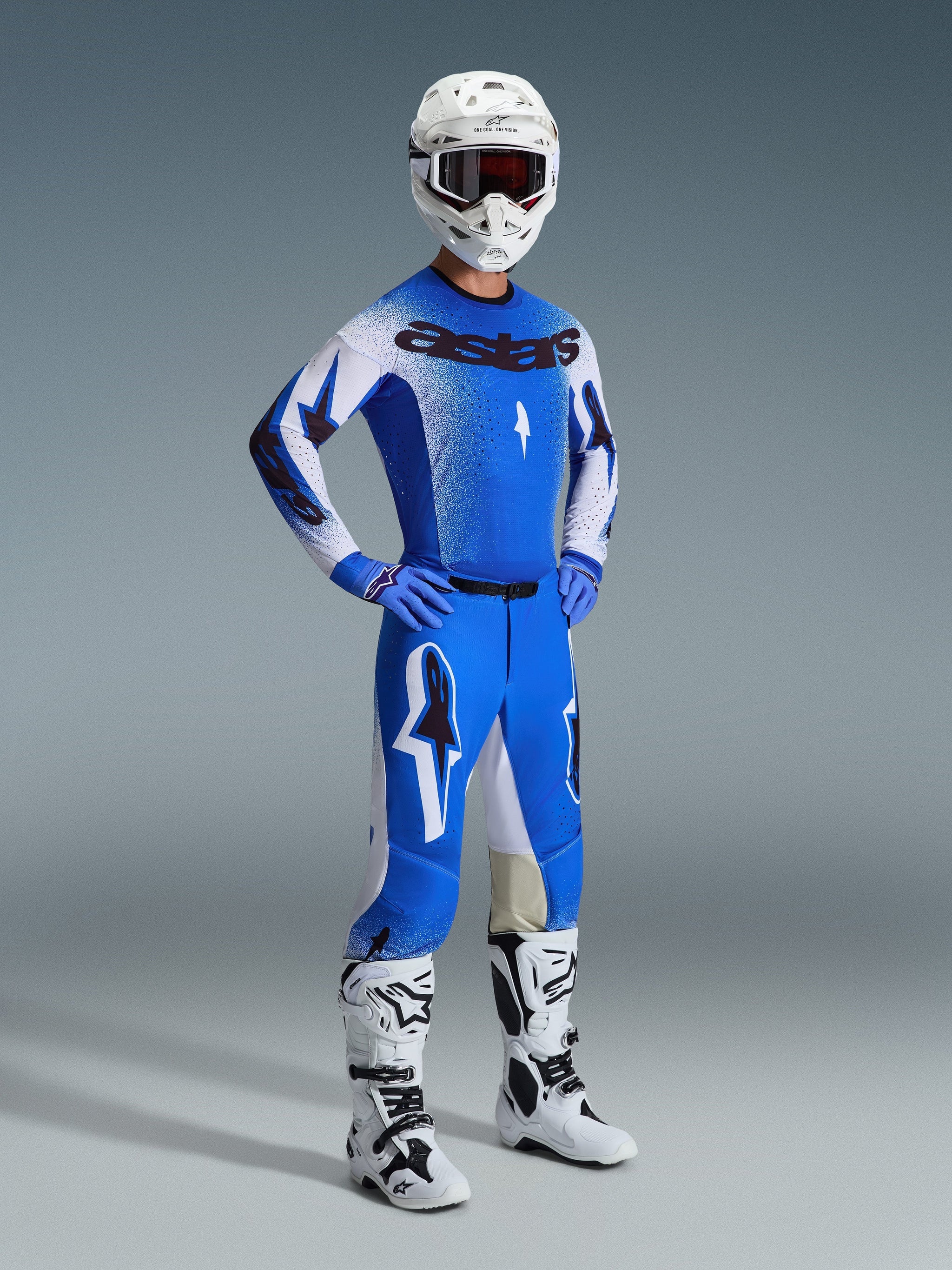 Motocross rider wearing the Alpinestars 2026 Supertech Scenz Gear Set in Ucla Blue and White, featuring a pro-level jersey with 'astars' branding, matching performance pants, white helmet, dark goggles, and white and black off-road boots.