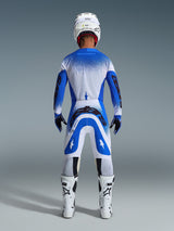Motocross rider from the back wearing the Alpinestars 2026 Supertech Scenz Gear Set in Ucla Blue White, blue and white jersey with black branding, matching pants, white helmet, and white boots, coordinated pro-level racing gear for off-road motocross