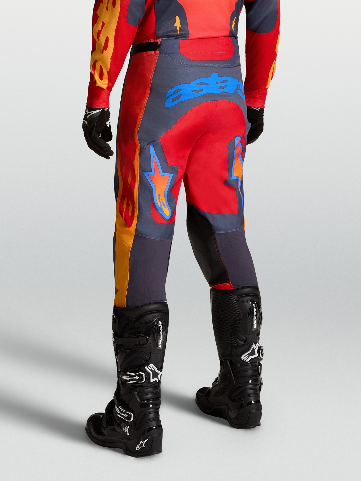 Alpinestars Racer Hunt Pants, performance motocross racing pants in Fire Red and Graystone, shown from the rear in a sport riding position.