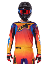 Alpinestars 2025 Fluid Wurx Jersey, Multicolor motocross jersey with orange and red gradient and purple accents, worn with matching gear, black helmet with blue and red goggles, and red gloves, featuring a large black star logo on the chest.