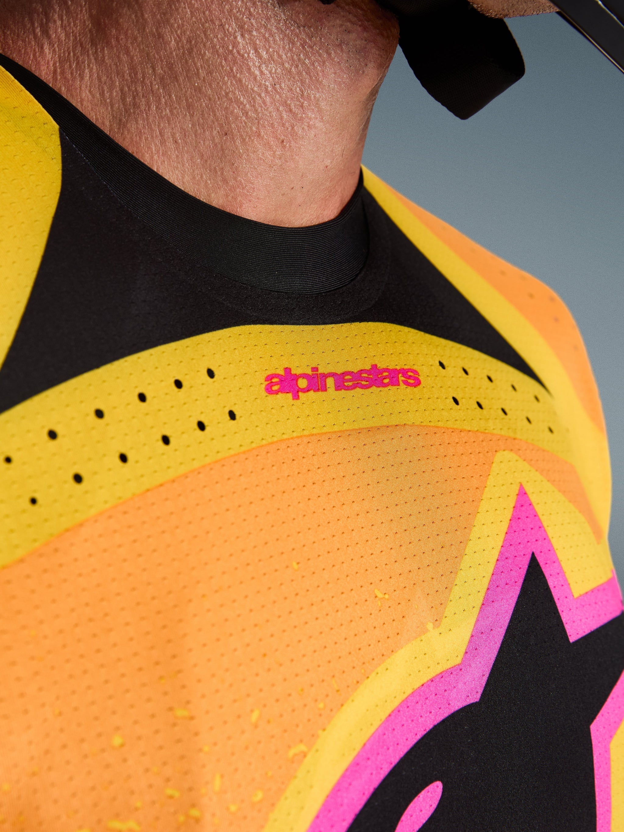 Alpinestars 2026 Techstar Nomur Jersey, Motocross Jersey, Orange Yellow Pink, close-up detail of the chest and collar, featuring laser-cut ventilation, pink branding, and breathable mesh fabric