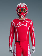 Alpinestars 2026 Fluid Apex Jersey, Motocross Jersey, Red and White, worn by a rider with a matching red and white helmet and orange goggles, featuring a prominent white logo on the chest, athletic fit, part of a coordinated off-road racing gear set