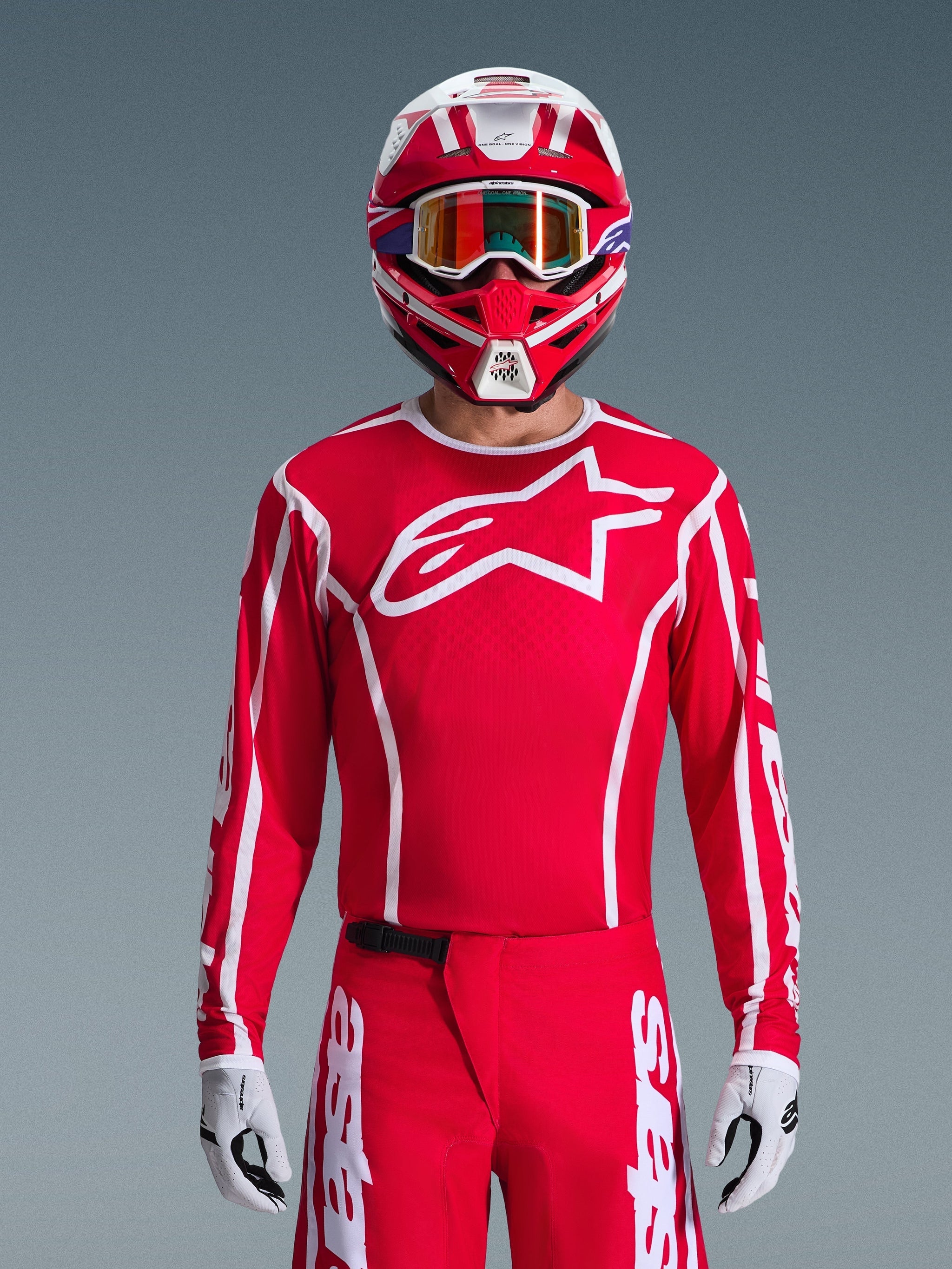 Alpinestars 2026 Fluid Apex Jersey, Motocross Jersey, Red and White, worn by a rider with a matching red and white helmet and orange goggles, featuring a prominent white logo on the chest, athletic fit, part of a coordinated off-road racing gear set