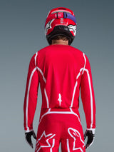 Rear view of a motocross rider wearing the Alpinestars 2026 Fluid Apex Jersey in Red and White, featuring geometric white patterns, styled with matching motocross pants and a red helmet, complete racing gear for off-road performance.