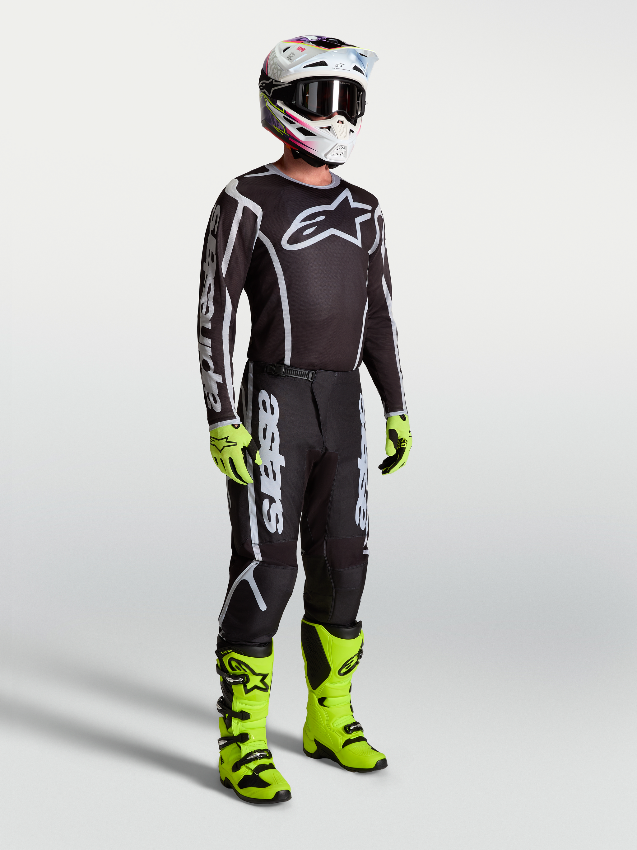 Alpinestars Fluid Apex V2 Jersey, Black and Silver motocross apparel on model with neon green boots and gloves.