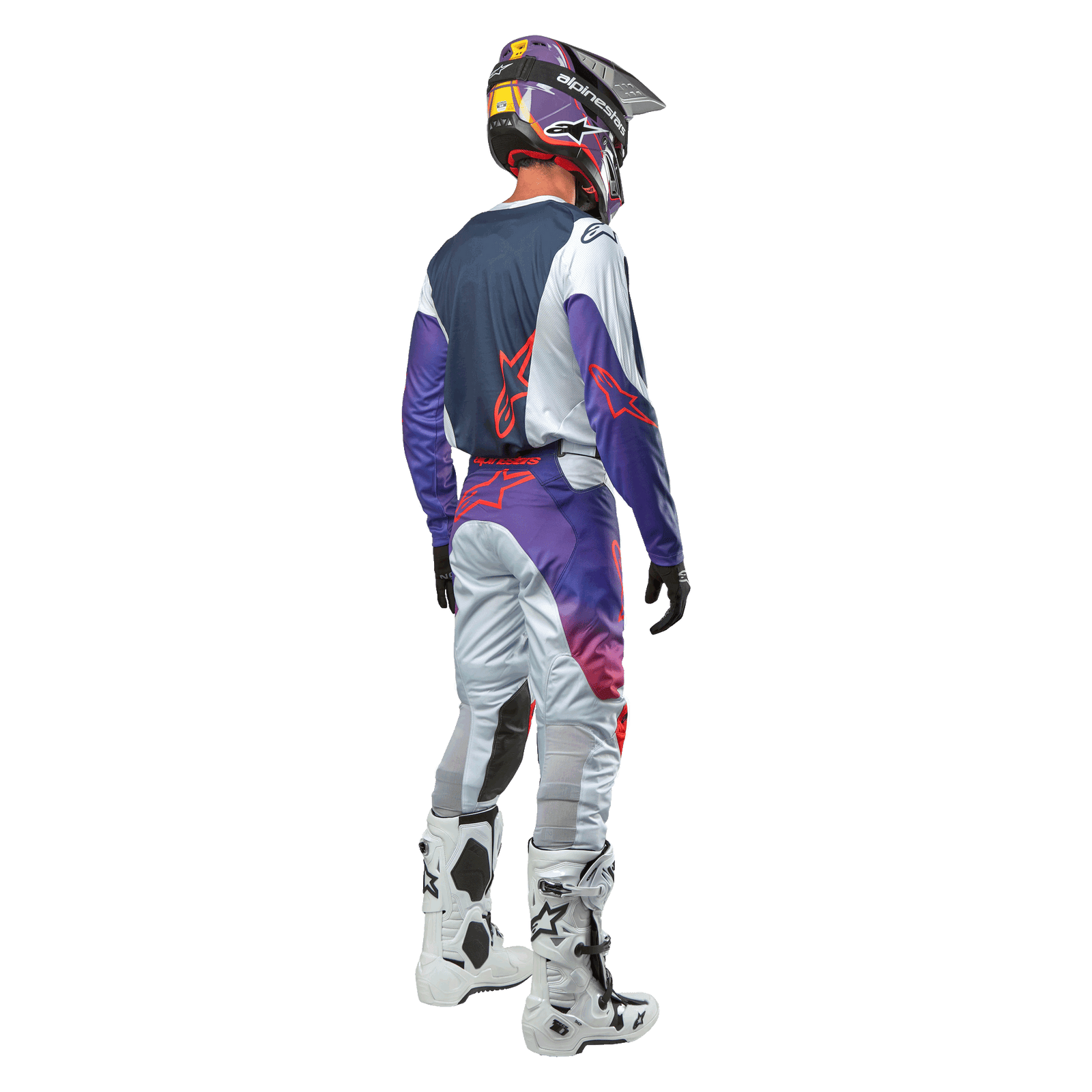Motocross rider seen from behind wearing the Alpinestars 2024 Racer Hoen Jersey in Light Gray Hot Orange Black, navy back panel with orange star logo, purple sleeves, worn with matching racing pants and white boots.