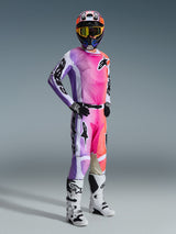 Motocross rider wearing complete racing gear featuring the Alpinestars 2026 Racer Air Portl Pants, vibrant pink, purple, and orange multicolor design with white accents, matching long-sleeve jersey, black helmet with yellow goggles, and white boots, coordinated outfit for high-performance off-road racing.