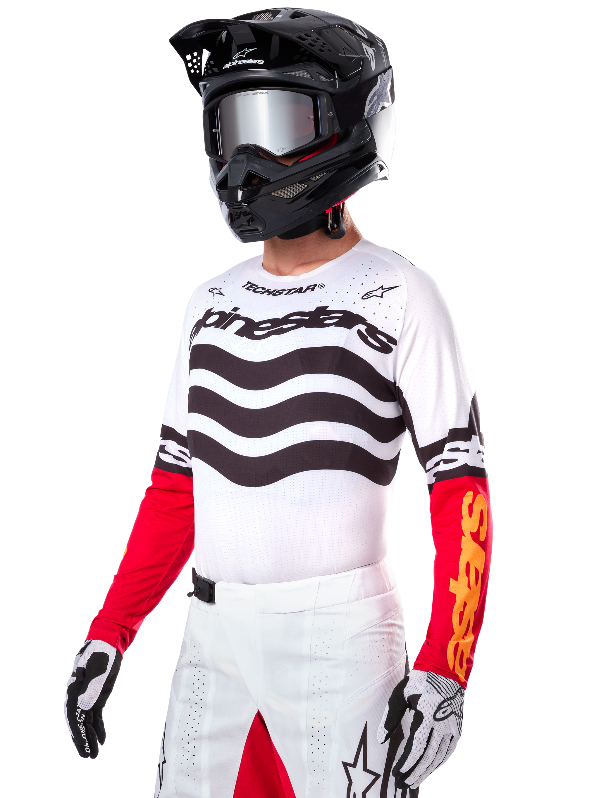 Motocross rider wearing the Alpinestars Limited Edition Techstar Deep Jersey, white jersey featuring black wavy stripes and red lower sleeves, styled with a black helmet, mirrored goggles, white and black gloves, and white racing pants, performance motocross outfit.