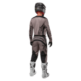 Alpinestars 2024 Fluid Lurv Jersey, Motocross Jersey, Mud Black, rear view of motocross rider wearing matching racing gear, black helmet, and white boots, featuring bold black Alpinestars logos and an athletic fit for off-road performance.