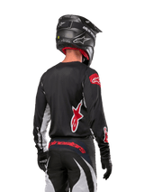 Alpinestars 2024 Fluid Lucent Jersey, Black and White motocross racing jersey with red logos, rear view on rider.