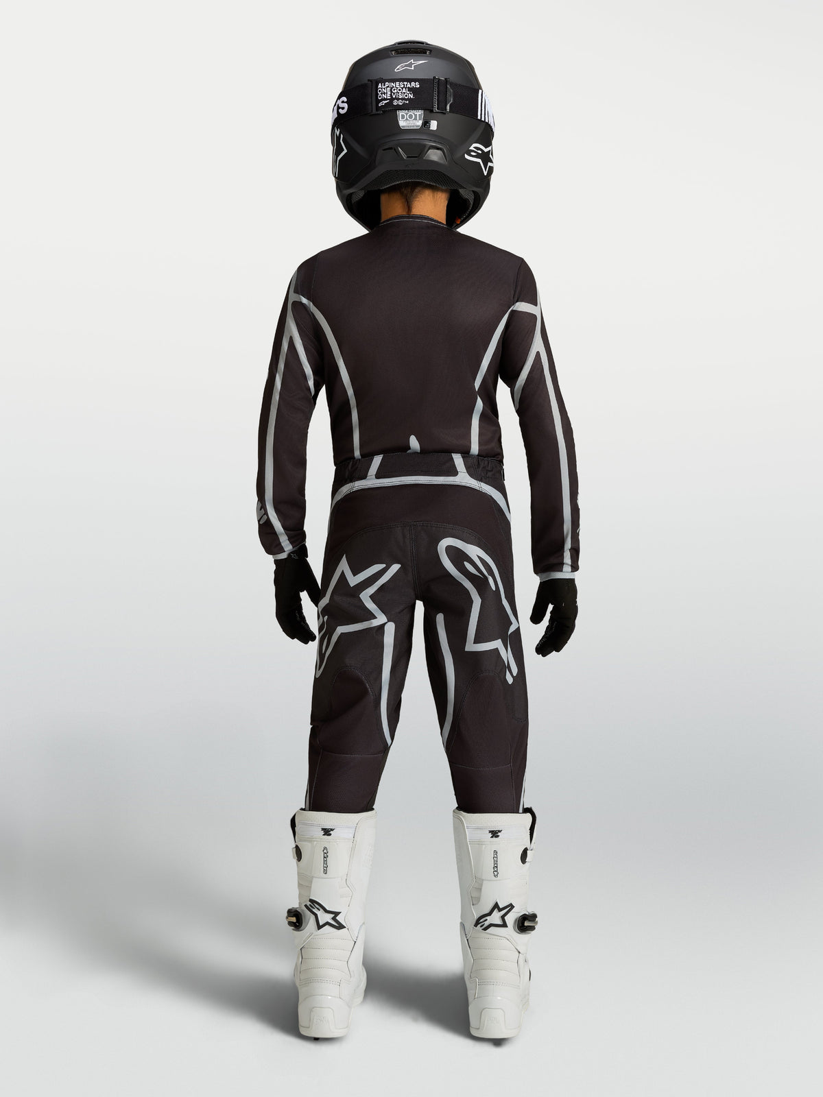 Alpinestars Youth Fluid Apex V2 Jersey and Gear Set, black and silver motocross kit with white boots, rear view.