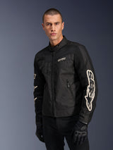 Alpinestars T-Dyno Air Jacket in Black, male model wearing a vintage-inspired textile motorcycle jacket with mesh panels for ventilation, large white Alpinestars logo on sleeves, paired with black riding gloves, urban motorcycle gear design