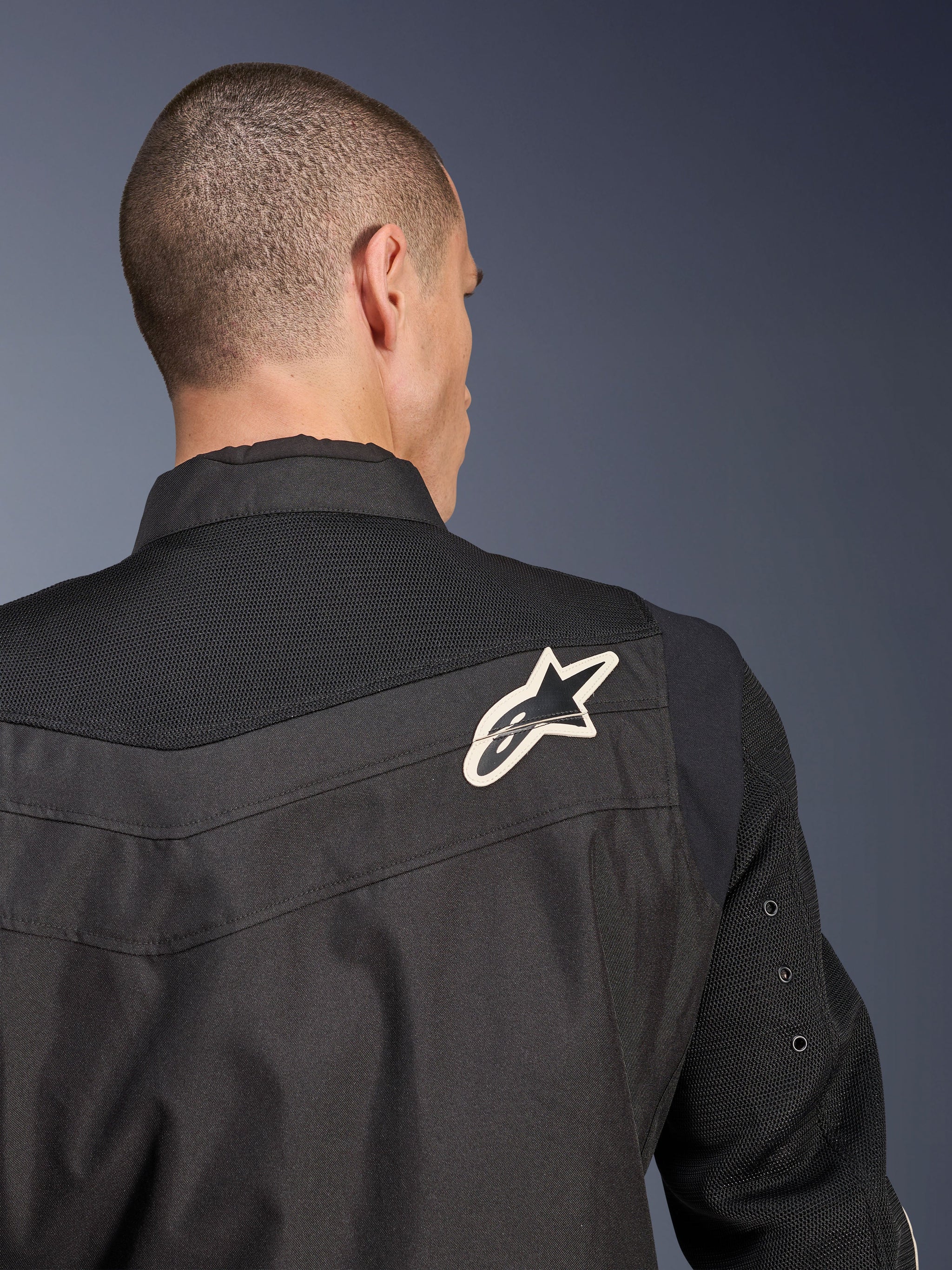Alpinestars T-Dyno Air Jacket, Black textile motorcycle jacket, close-up back view highlighting the breathable 3D mesh yoke and sleeves, featuring a white and black star logo on the right shoulder.