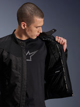 Alpinestars T-Dyno Air Jacket, Black, male model showing the internal mesh lining and waterproof compartment label, worn over a black graphic t-shirt, modern urban motorcycle riding gear