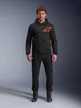 Alpinestars Chrome Air Sport Hoodie, Black and Red Fluo, Urban Motorcycle Riding Jacket with tech fleece construction, featuring a large red Astars logo on the chest and branding on the sleeve, worn by a model with black pants and riding shoes