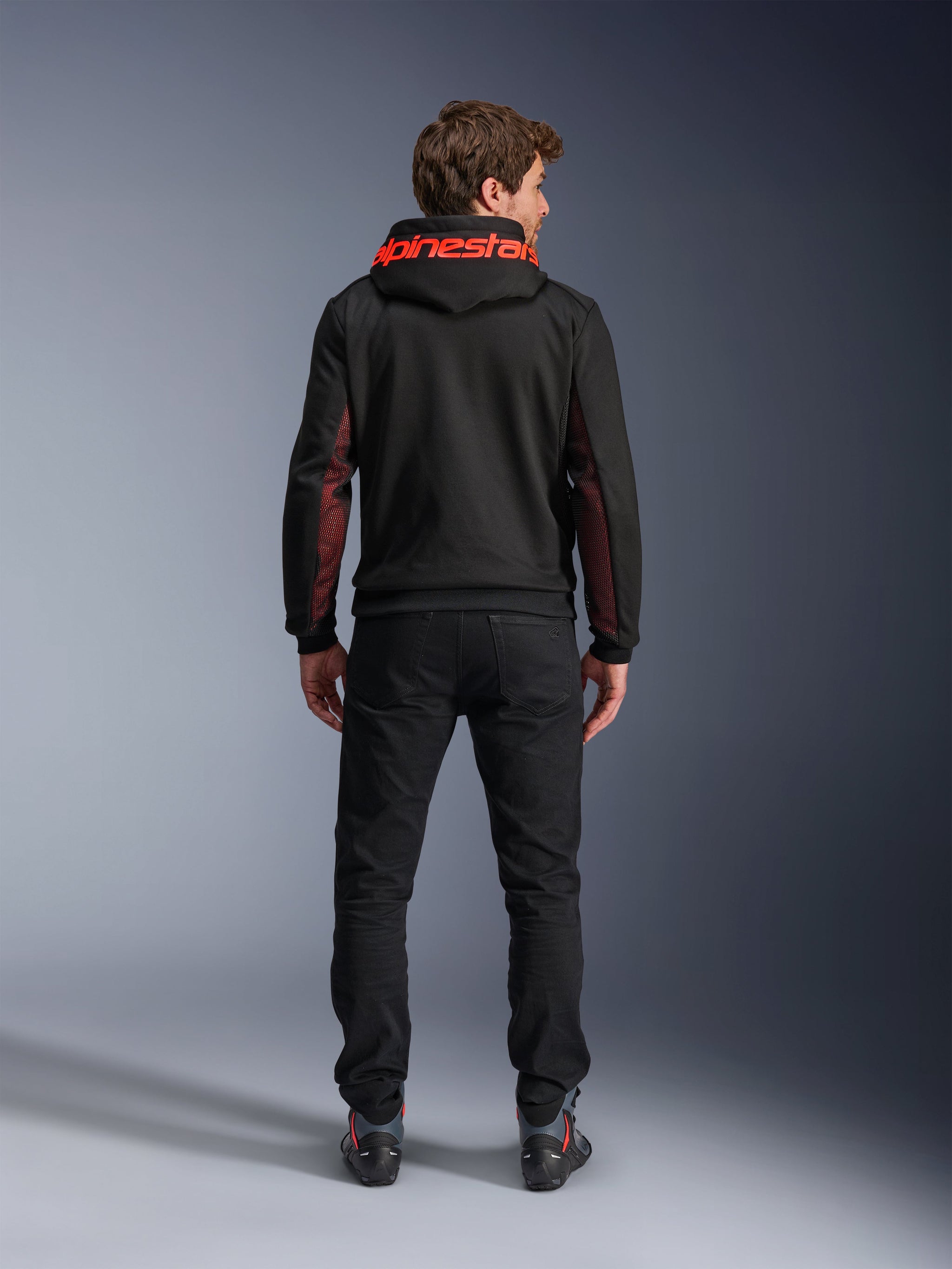 Alpinestars Chrome Air Sport Hoodie, Black and Red Fluo, back view of man wearing casual motorcycle jacket, featuring red Alpinestars branding on the hood and red mesh panels on the sleeves, paired with black pants.