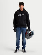Alpinestars Ageless Hoodie, men's urban motorcycle hoodie in black with a prominent white Astar logo on the chest, worn by a model holding a helmet and wearing riding gloves, casual CE certified protective motorcycle apparel.