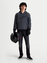 Alpinestars Ageless Hoodie, men's urban motorcycle hoodie in asphalt melange gray, front view on a model wearing black riding gloves and holding a helmet, featuring integrated shoulder and elbow protection.