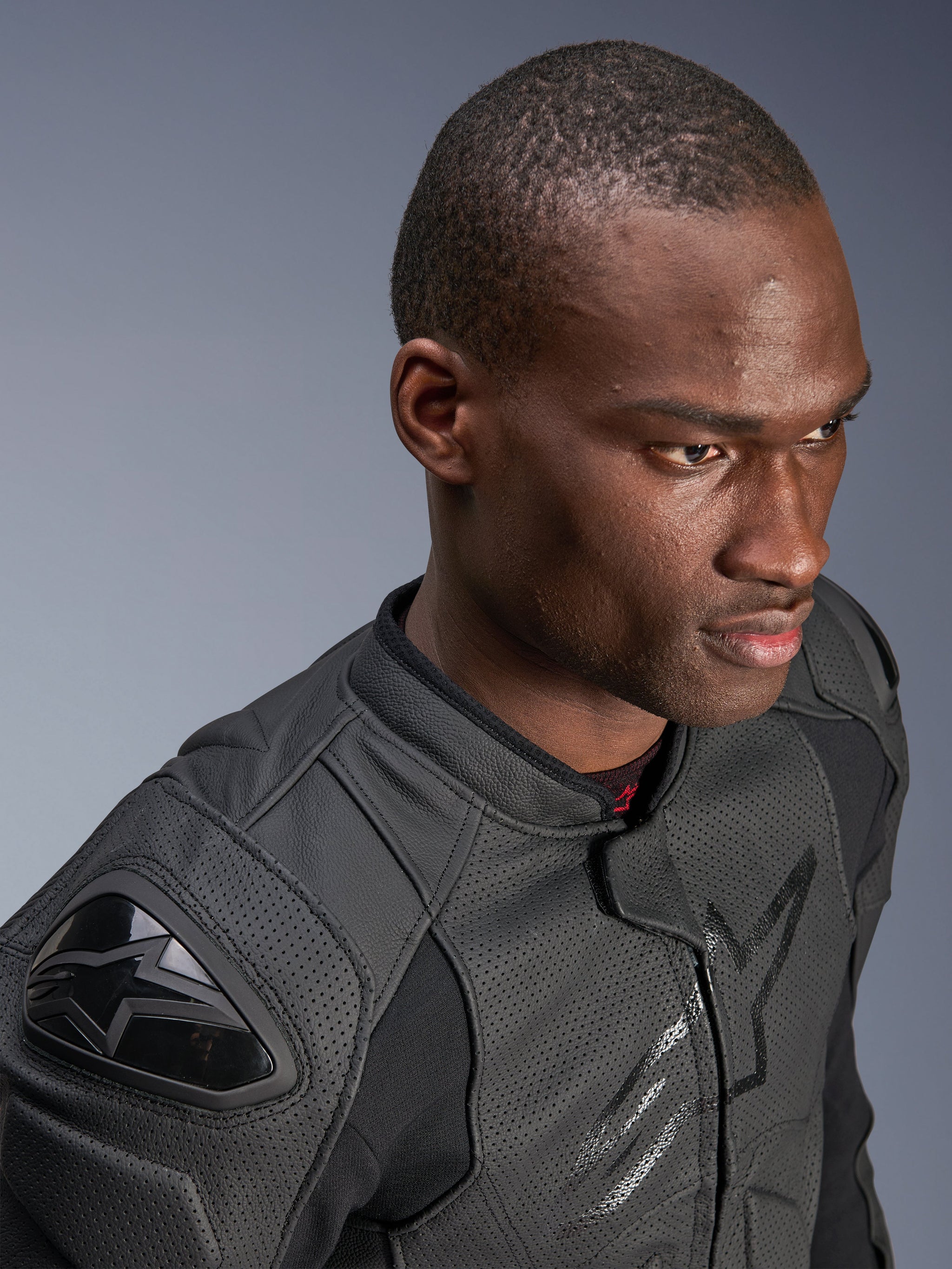 Close-up of a model wearing the Alpinestars Dusk Airflow Leather Jacket, Black on Black, featuring extensive perforated leather for breathability, external DFS shoulder sliders, and a sleek modern design for sport riding.