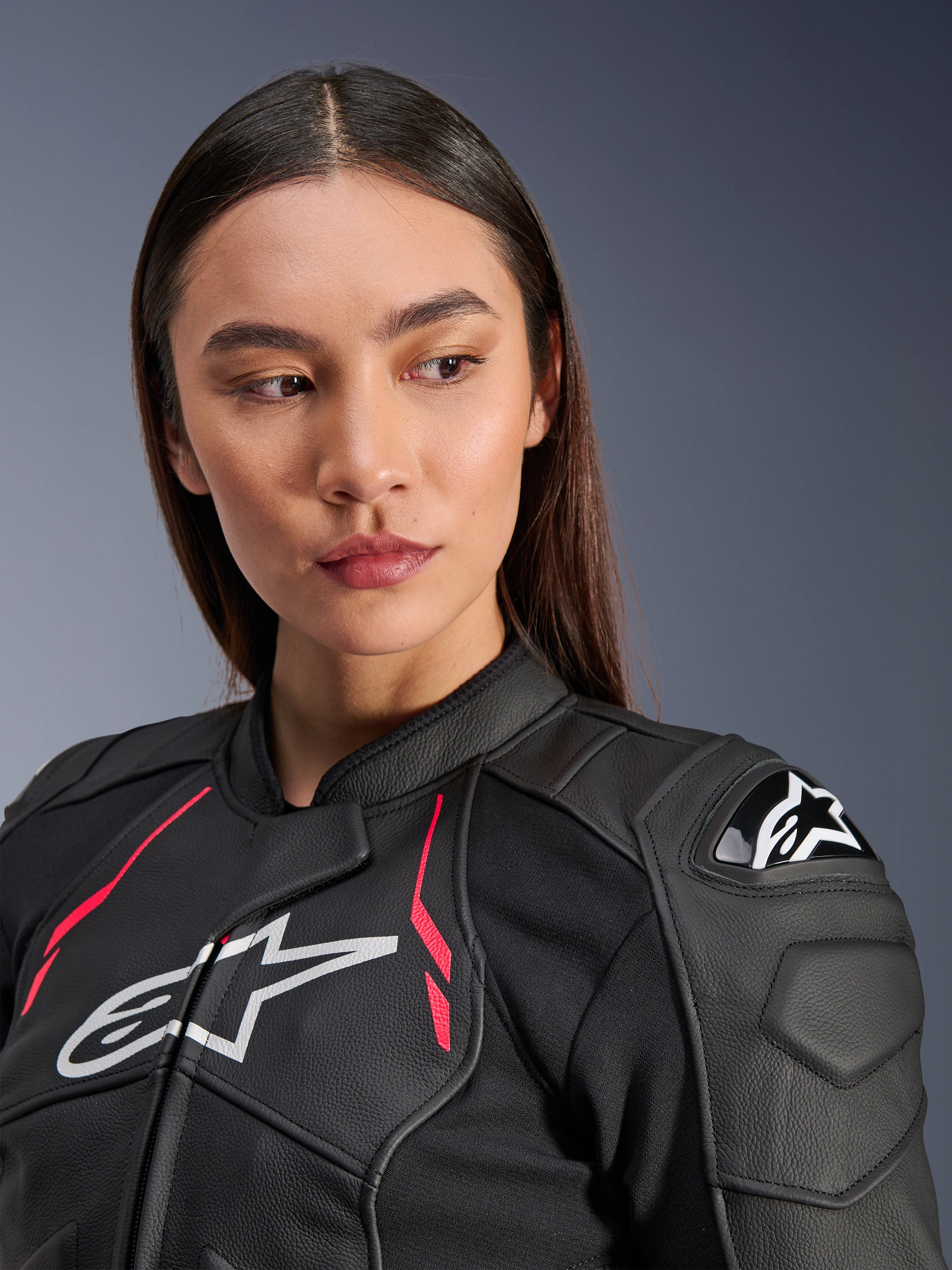 Woman wearing the Alpinestars Stella Dusk Leather Jacket in Black Diva Pink White, featuring a white chest logo, vibrant pink accents, and external DFS shoulder protection, premium bovine leather motorcycle gear