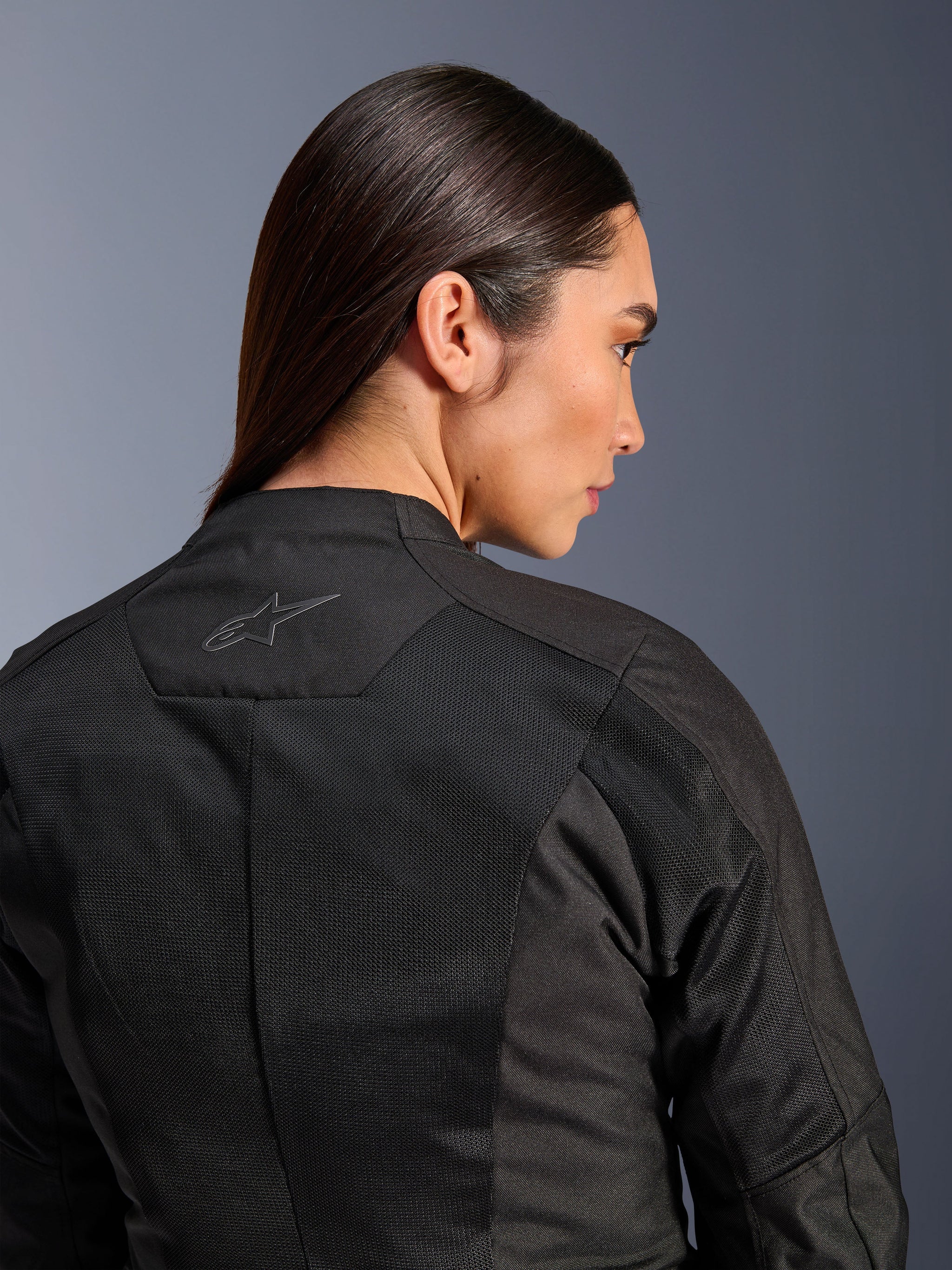 Alpinestars Woman Stella C-1 Air Jacket, Textile Motorcycle Jacket, Black, close-up rear view showing tech mesh ventilation panels and a reflective star logo on the upper back, modern urban riding gear